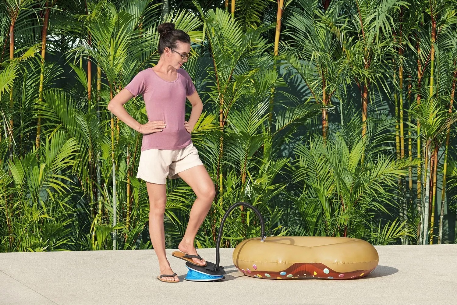 Žena používá nožní pumpu Bestway Air Step Pro k nafouknutí plovacího kruhu ve tvaru donutu. Žena používá nožní pumpu Bestway Air Step Pro k nafouknutí plovacího kruhu ve tvaru donutu.