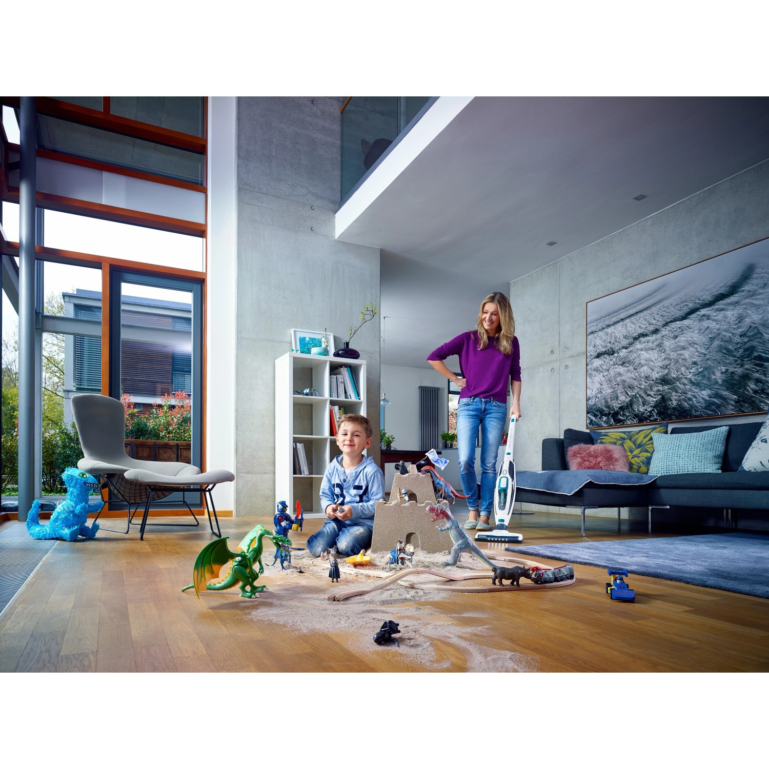 Akumulátorový vysavač Leifheit Regulus PowerVac v akci, matka vysává prach z hraček, dítě si hraje. Akumulátorový vysavač Leifheit Regulus PowerVac v akci, matka vysává prach z hraček, dítě si hraje.