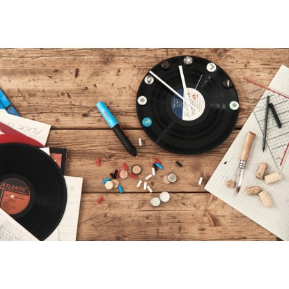 Tavná lepicí pistole Bosch Gluey Lagoon Blue na pracovním stole s vinylovými hodinami a řemeslnými potřebami. Tavná lepicí pistole Bosch Gluey Lagoon Blue na pracovním stole s vinylovými hodinami a řemeslnými potřebami.