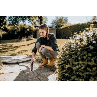 Žena čistí terasu víceúčelovým vysavačem. Praktické čištění zahrady. Žena čistí terasu víceúčelovým vysavačem. Praktické čištění zahrady.