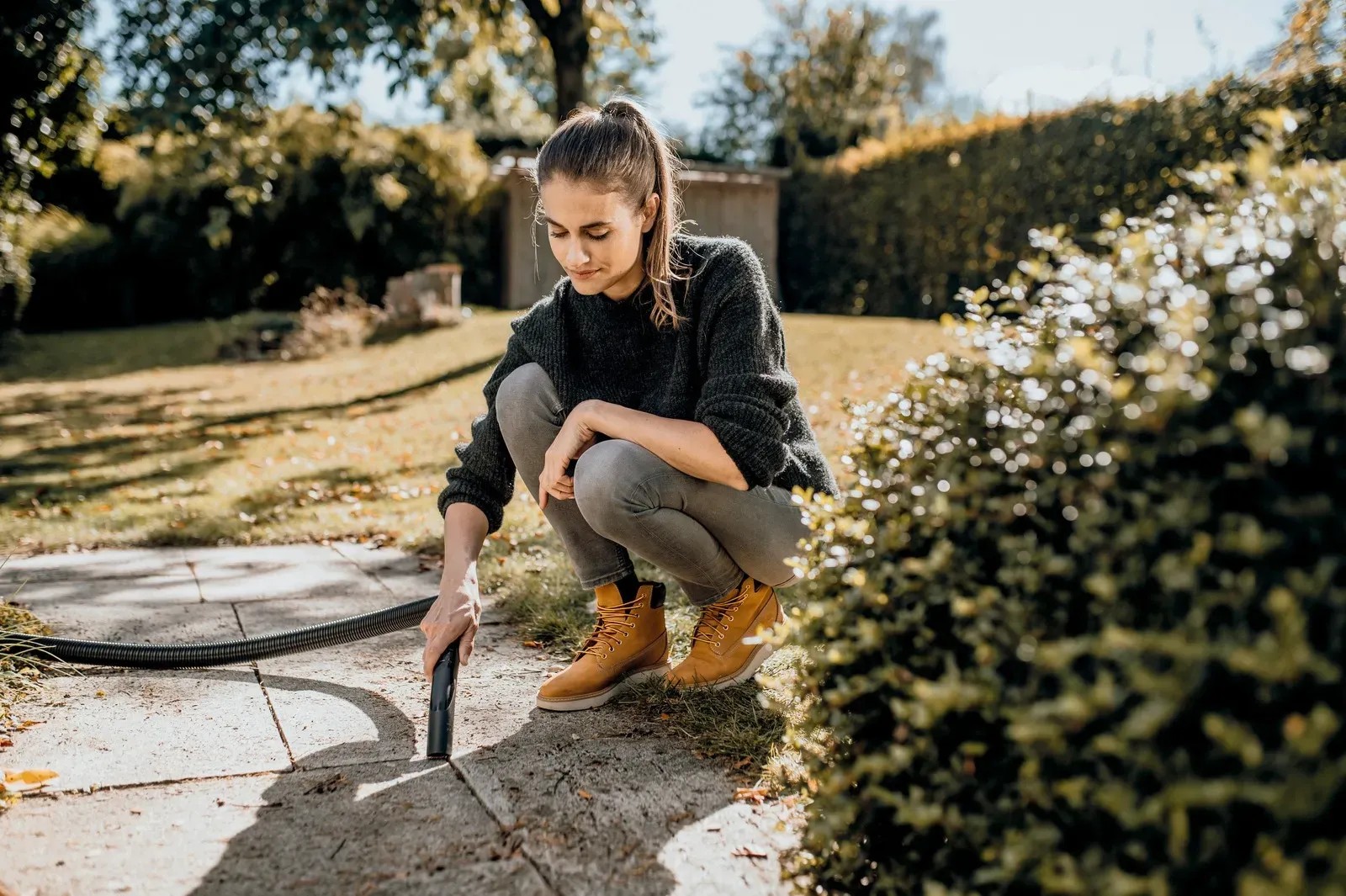 Žena čistí terasu víceúčelovým vysavačem. Praktické čištění zahrady. Žena čistí terasu víceúčelovým vysavačem. Praktické čištění zahrady.