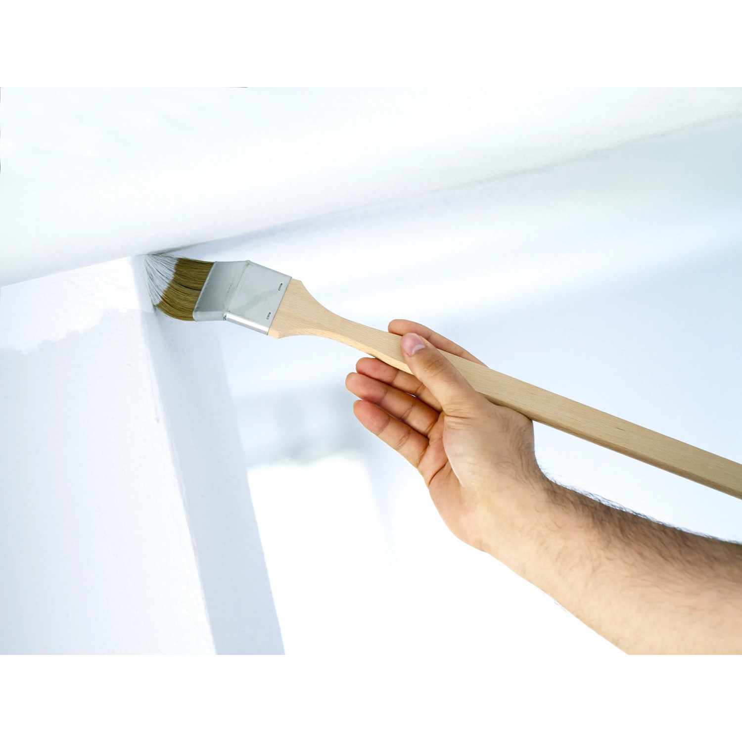 Rohový štětec LUX 50 mm v akci: Ruka maluje roh disperzní barvou. Rohový štětec LUX 50 mm v akci: Ruka maluje roh disperzní barvou.