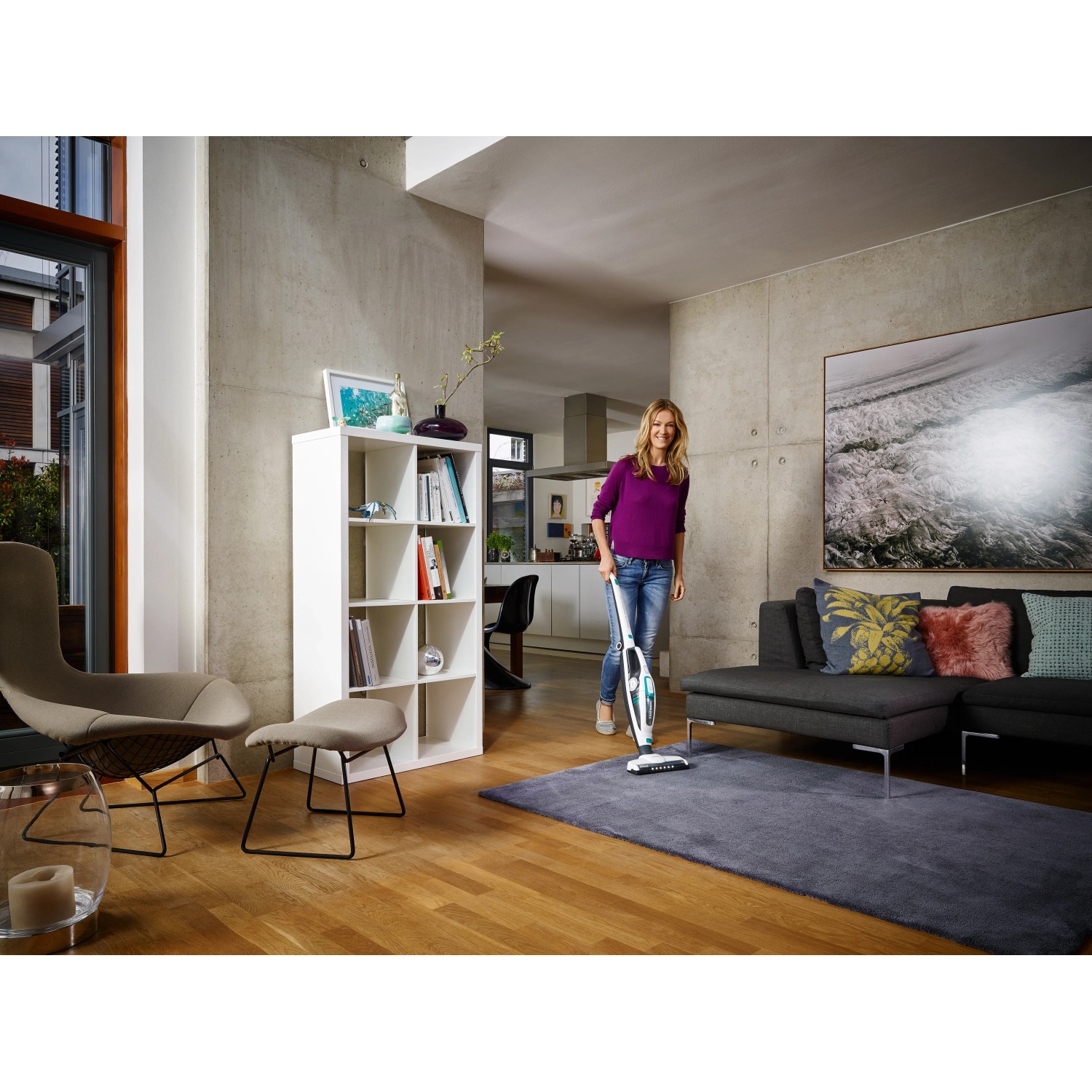 Žena vysává koberec pomocí akumulátorového vysavače Leifheit Regulus PowerVac. Akumulátorový ruční vysavač. Žena vysává koberec pomocí akumulátorového vysavače Leifheit Regulus PowerVac. Akumulátorový ruční vysavač.