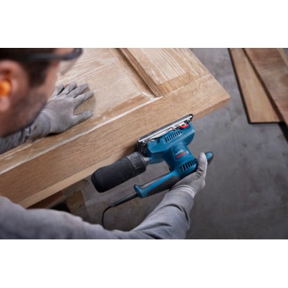 Excentrická bruska Bosch Professional GSS 20-18 A při broušení dřevěných dveří.